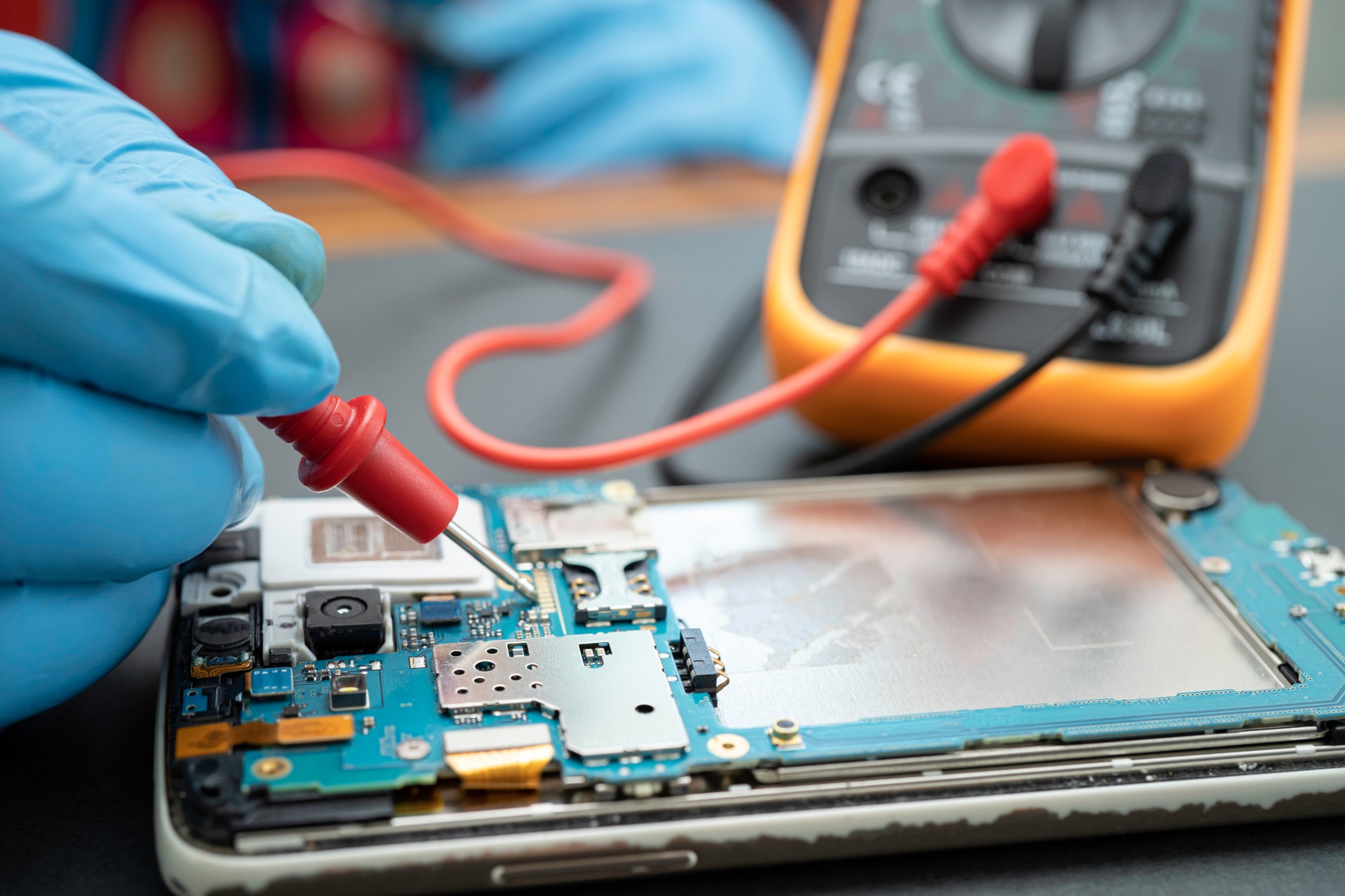 Technician repairing inside of mobile phone by soldering iron.