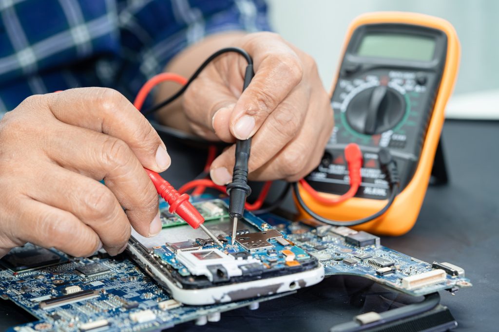 Technician repairing inside of mobile phone by soldering iron. Integrated Circuit.