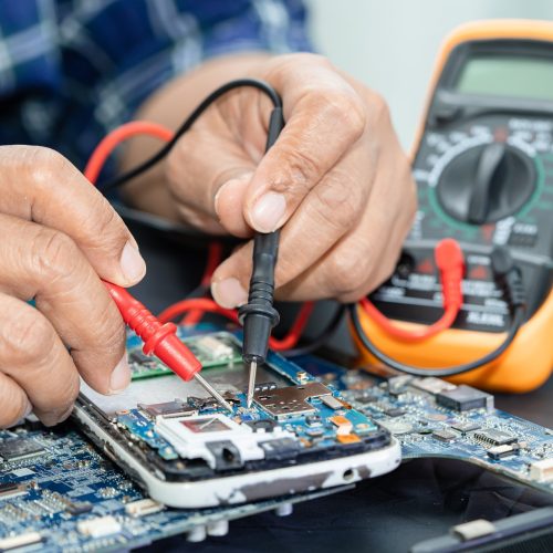 Technician repairing inside of mobile phone by soldering iron. Integrated Circuit.