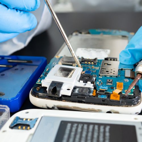 Technician repairing inside of mobile phone by soldering iron